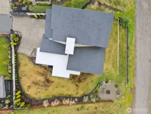 Modern exterior of a contemporary home for sale in the River Rock subdivision, featuring clean architectural lines, stone accents, a spacious driveway, and attached garage. Aerial and front views highlight its setting within the scenic River Rock community surrounded by natural greenery.