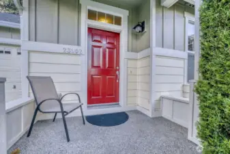 Welcoming front porch surrounded by beautiful mature trees and greenery.