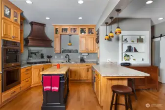 Gourmet kitchen featuring a double oven, gas stove and tall back lit craftsman cabinets.