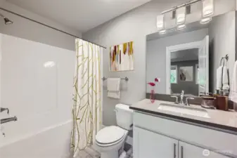 Full bath with shower-tub combo and quartz counters on lower level.