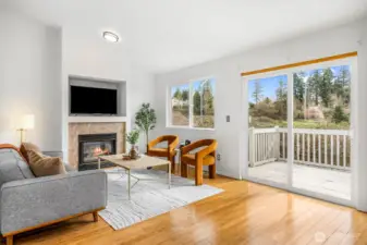 The living room features a gas fireplace and a sliding glass door opening directly to the deck with peaceful backyard views.