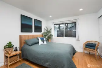 The primary bedroom features two closets, attic storage, and windows that flood the space with natural light.