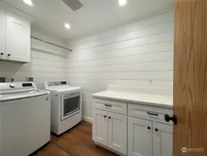 Large laundry room with hanging rack, lots of cabinet space and a countertop for folding clothes and keeping things neat and organized.