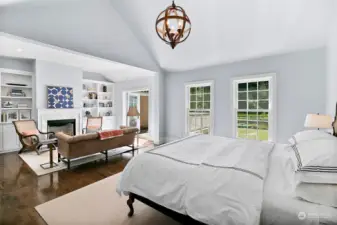 Primary bedroom, on the main level, with vaulted ceilings and sitting area.  Gas fireplace and French doors leading out onto the entertainment sized deck and backyard oasis.