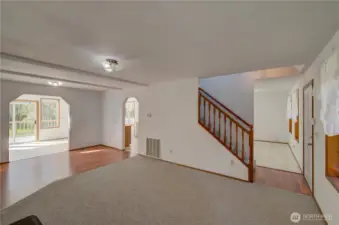 Looking through the living room towards the dining room, stairs to the upper bedrooms, kitchen and sun room.