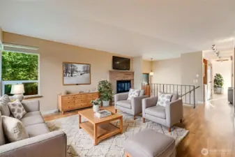 Virtually staged large living room with a fireplace.  Bright and airy with large windows.