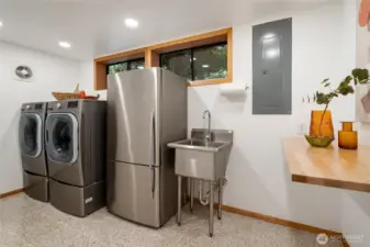 Huge laundry room with quality washer and dryer, extra fridge, a utility sink, and extra storage space.