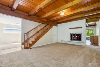 Throughout most of the first floor, there are wood ceilings and beams, adding a warm ambiance to the home. All were refinished in 2018. The living room is further enhanced by a wood-burning fireplace nestled in a white brick wall, completing the cozy atmosphere.