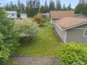 Behind the home with mature trees - but nothing huge that looms over the home.