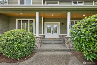 Oversized, cedar-lined front porch with French door entry and rock accents.
