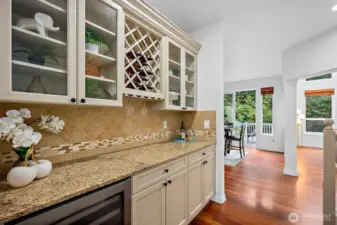 Butler pantry is located between the formal dining room and kitchen and has granite counters with full tile backsplash, custom cabinetry with wine rack and a stainless steel wine/beverage fridge.