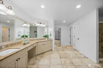 Huge primary suite bathroom has oversized tile flooring and granite counters with undermount sinks.