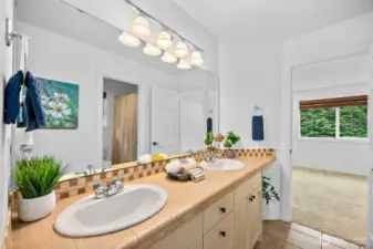 The en-suite/Jack and Jill bathroom for bedrooms 3 and 4 has dual vanities, tile counters and tile flooring.