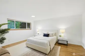 Spacious primary bedroom with large window and clean, modern finishes.