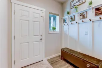 Entry has laminate vinyl flooring and tall ceilings and a window for natural light.
