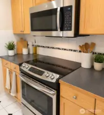 Range and microwave in the kitchen.  Photo has been enhanced to better showcase the space.