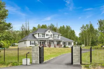 This grand residence is framed by a wrought-iron fence, paved driveway, RV parking, and a shop with ADU