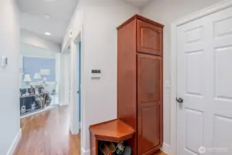 Small bench with shoe storage and tall cabinet for coats for additional storage.