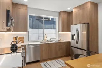 Enjoy natural light and clean lines in this gourmet kitchen featuring quartz counters, a full-height backsplash, and gold-tone fixtures.