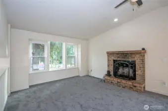 Warmth and charm fill the living area with a brick wood fireplace and new carpet.