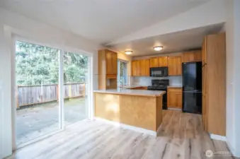 Dining area view into the updated kitchen, with new laminate hardwood flooring enhancing the space.