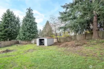 Additional view of the fenced backyard.