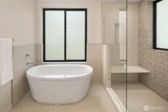 The primary suite includes a sleek soaking tub for relaxation. Color of tiles will vary