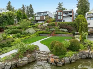 Beautifully landscaped low bank waterfront, large grassy area, stone path from dock to residence and fire pit