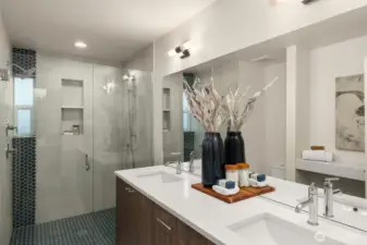 Pamper yourself in the beautifully designed ensuite bath, showcasing a sleek double vanity, luxurious finishes, and an expansive glass-enclosed shower—a space to indulge in ultimate comfort. Photos of home with similar layout, finishes & fixtures.