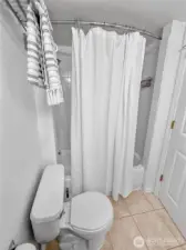 The tub/shower combo has a curved curtain rod and there is a towel rod / shelf over the toilet.