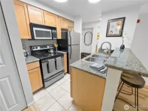 Another view of the kitchen and eat-in bar, this time from the dining room. The bathroom and entry are in the background.