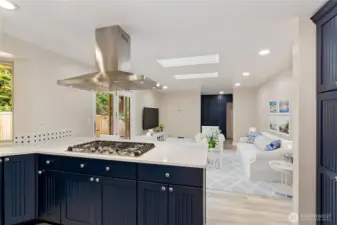 Kitchen gas cooktop, quartz counter tops, stainless hood. Virtually staged family room in the background