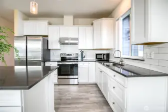 Classic tile backsplash adds to the beauty.  And not to worry!  If you want a dishwasher, the plumbing is next to the sink and it would be easy to remove the end storage to install the appliance.