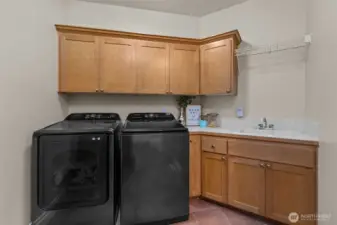 Well-appointed laundry room with cabinetry and counter space for added convenience.