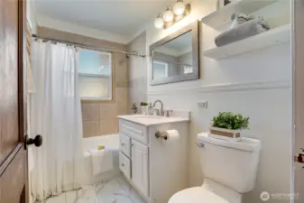 Find the updated full bath right across the hall with its tile tub surround and privacy glass window.