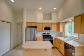 Kitchen looking towards front entry hallway, showing double door pantry, door to half bath.