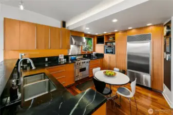 Sleek walnut cabinetry and soapstone counters frame a chef’s kitchen fully equipped with Viking range, SubZero refrigeration, Miele dishwasher, Bosch oven, and beverage fridge. Surrounded by treetop windows, even daily cooking feels immersed in Olmsted’s woodland calm.