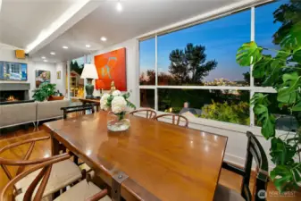 Evening settles as city lights shimmer beyond the treetops, glimpsed through floor-to-ceiling glass. From this dining table, the glow of the University District and Portage Bay unfolds like a living canvas framed by Olmsted’s woodland.