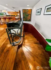 A dramatic serpentine stair curves downward, its walnut treads and sculptural lines carrying the home’s rich materiality into the garden level. This graceful transition links main-floor living to versatile suites and workspaces below.