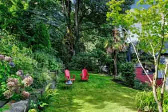 A grassy clearing offers a quiet counterpart to the home’s decks and patios, framed by hydrangea and woodland understory. Set within Interlaken Park’s living tapestry, it’s a place for pause, conversation, and the restorative calm of nature.