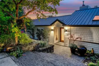 At dusk, the front entry glows with a quiet welcome, framed by woodland plantings and the shelter of a private lane. This is the threshold to a rare Interlaken residence—secluded in the park, yet minutes from the energy of North Capitol Hill.