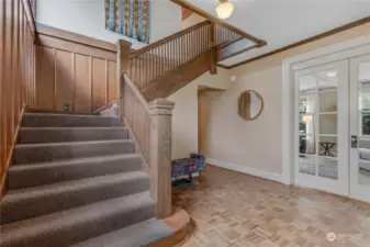 Large welcoming area with grand stair case and french doors leading to the front room.