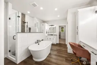 Spa-like retreat in the primary bathroom suite! Luxurious soaking tub, roomy walk-in shower, two vanities, water closet. Abundant storage, worry-free luxury vinyl plank flooring. Doorway in center leads expansive closet.