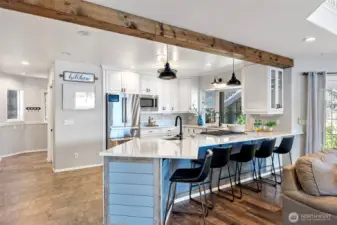 Gorgeous open kitchen with white cabinets and countertops and seating area.