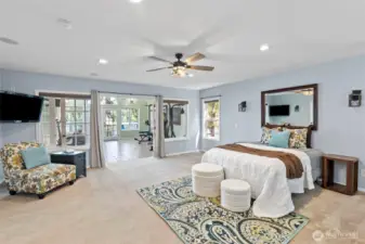 Primary suite  with in room sink vanity and french doors to the flex space with the lake beyond.