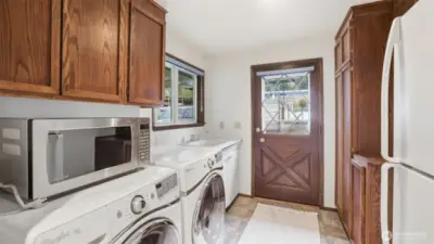 Well-equipped laundry space featuring generous storage, full-size appliances, and a handy utility sink.