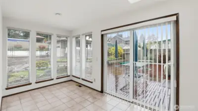 Light-filled sunroom with floor-to-ceiling windows and easy access to the backyard deck.