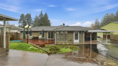 Generous outdoor space with a blend of deck, lawn, and covered parking—ideal for year-round use