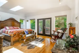 Large primary bedroom with custom fireplace and french doors leading to the deck.