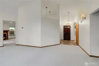 Spacious living room with vaulted ceilings, numerous windows, and dining area